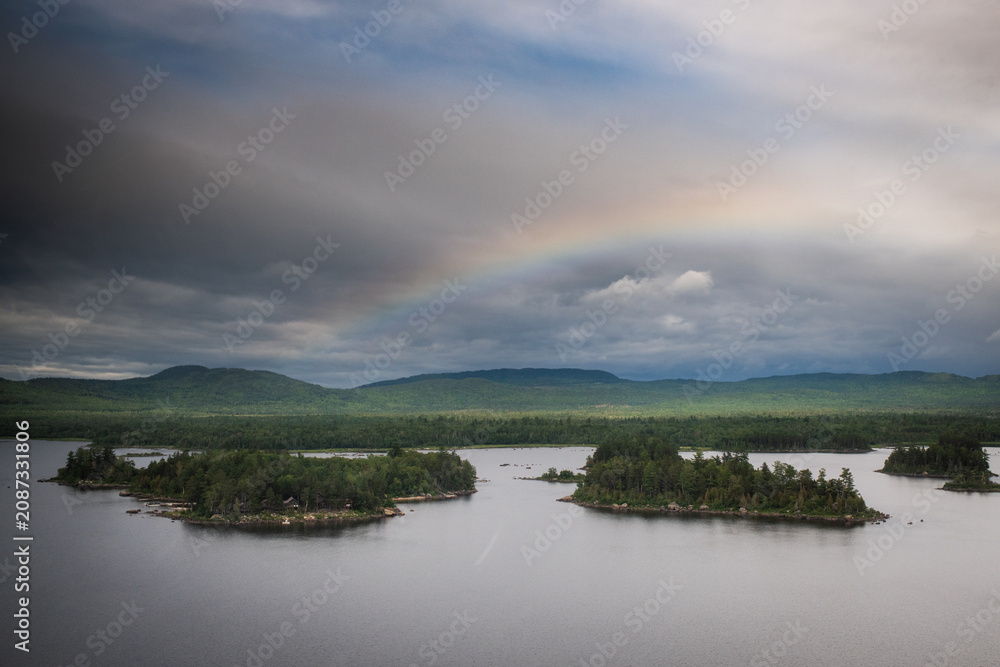 Obraz premium Rainbow over forested islands and lake