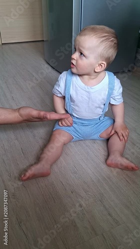 Mother teaching baby boy to give high five at home