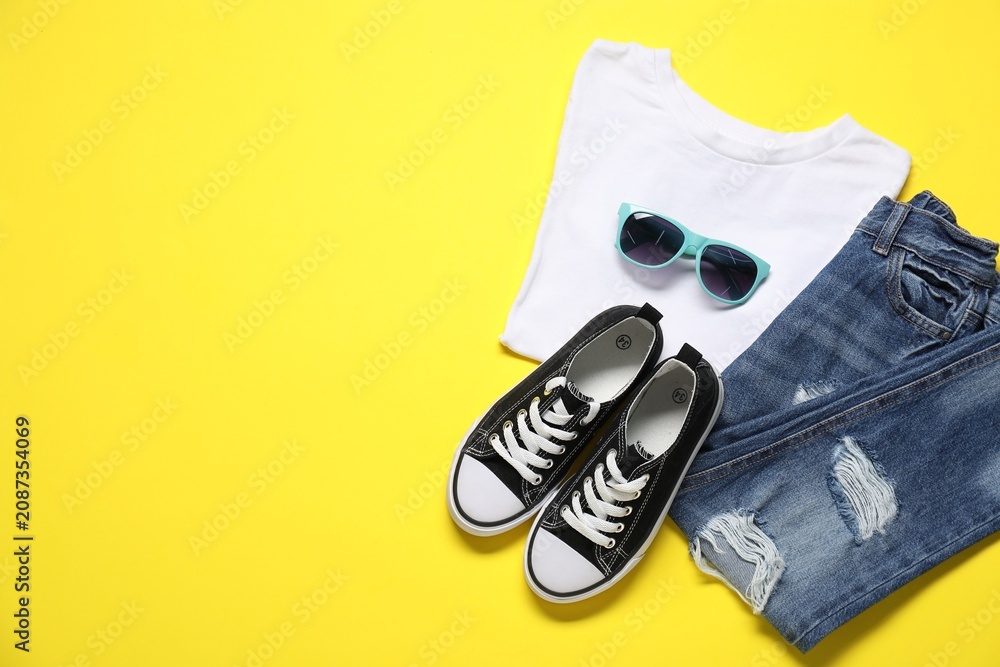 Obraz premium Stylish child's clothes, sunglasses and shoes on yellow background, flat lay. Space for text