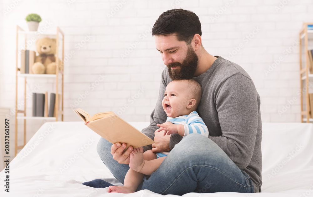 Obraz premium Adorable baby spending happy time with daddy, reading book together, copy space