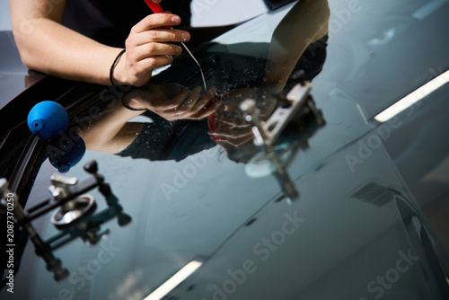 Φωτογραφία Expert mechanic performs a final glass fracture inspection using a scriber tool