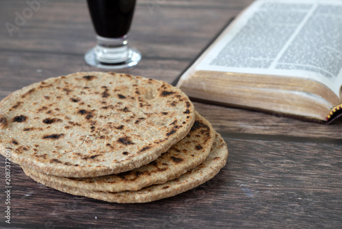 Obraz na płótnie Unleavened bread with holy bible book and glass of wine on wooden table