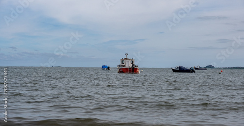 Boats moored on the choppy waters off Holy Island, Northumberland coast, swaying against the waves beneath a dramatic, wind-ruffled sea.