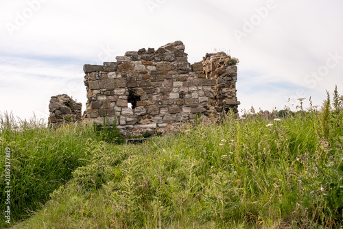 Historic stone ruins stand at the lookout point on Holy Island, Northumberland coast, weathered by time and overlooking the sweeping coastal landscape.
