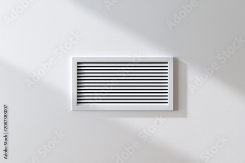 White air vent grille mounted on a smooth wall with soft shadows and natural light highlighting texture
