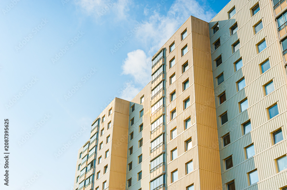 Fototapeta premium Modern beige residential apartment building under bright blue sky.