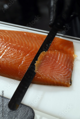 Fotografie chef cortando lomo de salmón ahumado en lonchas finas con un cuchillo de corte f