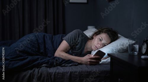 Woman Lying in Bed at Night Checking Smartphone Unable to Sleep