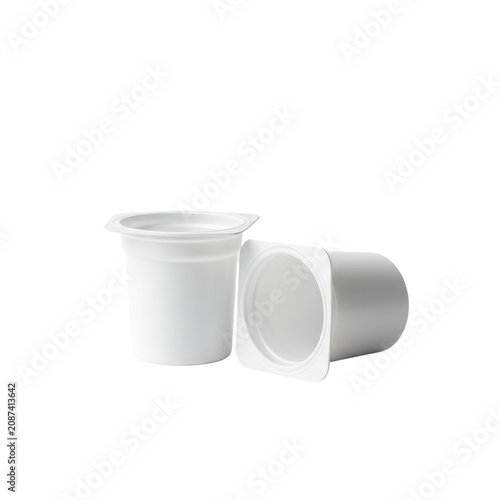 Two identical, empty, white plastic single-serving yogurt containers, one upright, one tipped, on a transparent background, concept of consumer waste, recycling, and material simplicity.