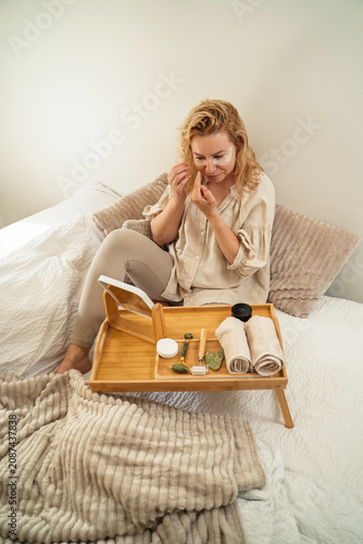 Pretty blonde woman putting eye gel patch, morning beauty routine
