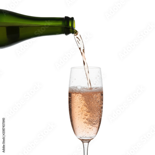 Dark forest-green glass bottle pouring rose-gold champagne into a slender crystal flute with sparkling bubbles in a bright minimalist studio celebratory atmosphere