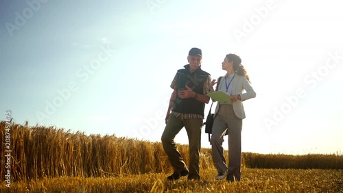 Farmer walking through a harvested wheat field with an agronomist, discussing crop results, harvest quality, agricultural planning and farm management.