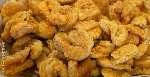 Crispy, golden-brown deep-fried pickle slices showing a textured cornmeal batter coating.