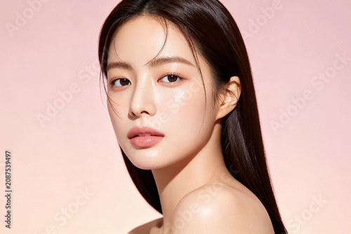 Young Asian Woman with Glowing Skin on Light Pink Background
