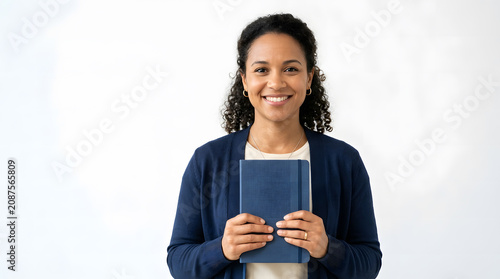 Woman smiling and holding a book against a white background
