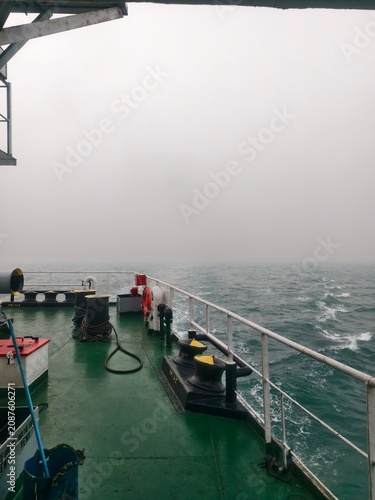 Photography View of the white foam and strong sea waves splashed from a cargo ship hull with a rope in the foreground