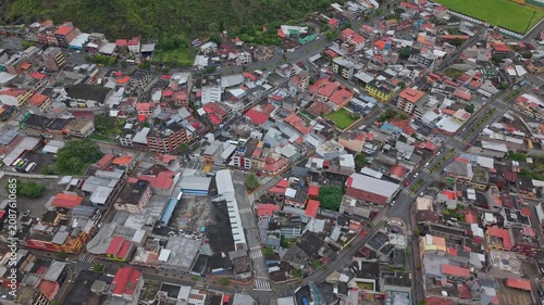 Aerial view of dense urban buildings and streets in Banos, Ecuador, near green hills