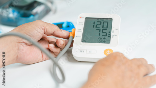 Tableau sur toile Close-up of a senior adult using a digital blood pressure monitor at home to measure systolic and diastolic blood pressure with pulse rate