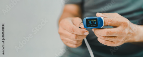 Bild auf Leinwand Close-up of a senior adult using a fingertip pulse oximeter to measure blood oxygen saturation and pulse rate at home