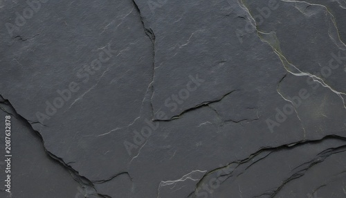 A detailed close-up of a dark grey slate stone surface with natural layers and jagged textures, showcasing the rugged and earthy appearance of this metamorphic rock used in wallpaper background
