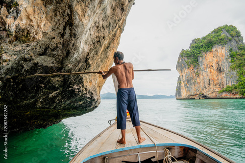 Принти на полотні Traditional longtail boatman navigating through limestone caves in thailand