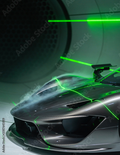 Carbon fiber sports supercar undergoing aerodynamic wind tunnel testing with green laser lights