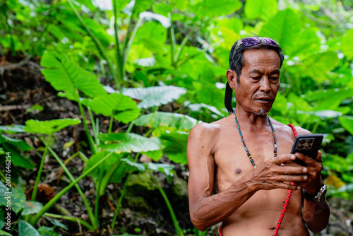 Indigenous man using smartphone in lush tropical forest