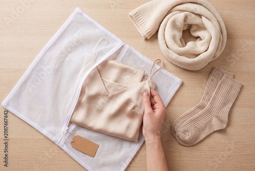 Person Placing Delicate Silk Clothing into a Mesh Laundry Bag for Washing