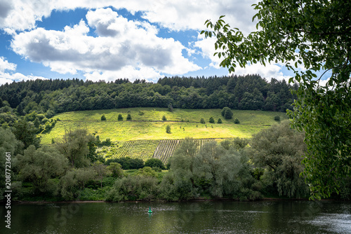 Das Licht tanzte über den Hang, während die Wolken ihre Schatten langsam über die Reben schoben. Die Mosel wirkte wie ein Spiegel, der Himmel und Landschaft zu einem einzigen Gemälde verschmelzen ließ