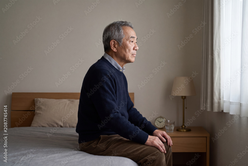 Fototapeta premium 寝室で一人静かに考え込むシニア男性。アジア人、日本人