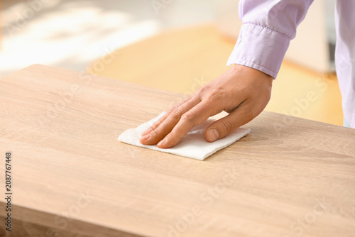 Hand wiping wooden table with cloth