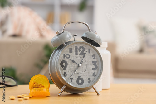 Canvastavla Alarm clock with pill bottles on table in room, closeup