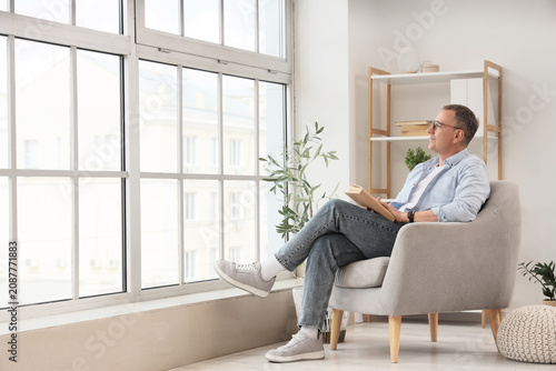 Man sitting in armchair rea...