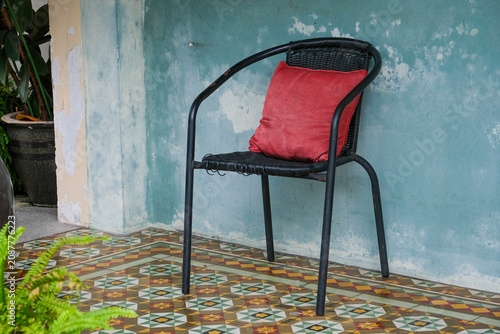 Vintage Chair on Traditional Peranakan Tiles Against Weathered Wall in George Town Penang Malaysia