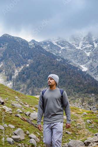 Young man hiking on a rocky mountain trail at Kareri Lake in Dharamshala with a peaceful atmosphere
