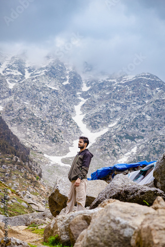 Hiker standing on rocky terrain at Kareri Lake in the snowy Himalayan mountains of Dharamshala