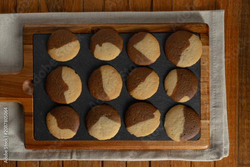 Home kitchen scene homemade chocolate and vanilla two tones Cookies resting on kitchen board, cooling and ready to eat on a rustic wooden table.