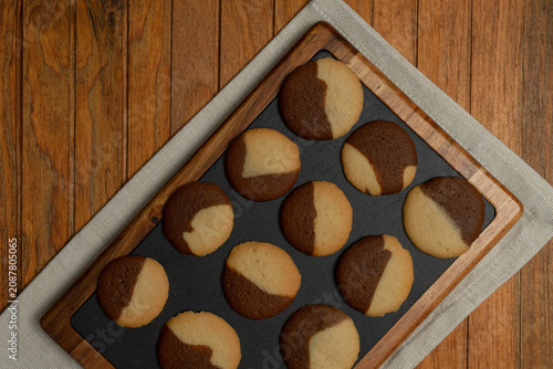 Homemade chocolate and vanilla two tones Cookies Home kitchen scene resting on kitchen board, cooling and ready to eat on a rustic wooden table.