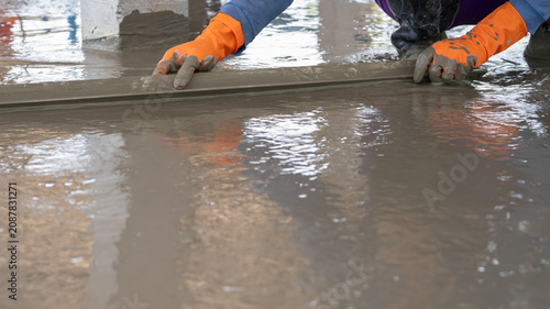 Fotografie Mason worker working with trowel to level cement floor at construction site