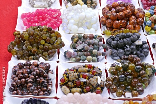 Cuadro en lienzo Assortment of colorful gemstone bead bracelets displayed in white bowls at a loc