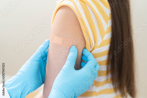 Obraz na plátně Close up of doctor applying adhesive bandage on girl arm after vaccination