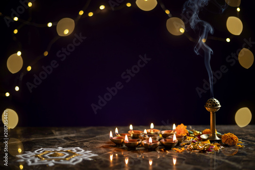 Diwali celebration with burning oil lamps and incense, traditional diya oil lamps on marble surface, festive background with bokeh lights and rangoli