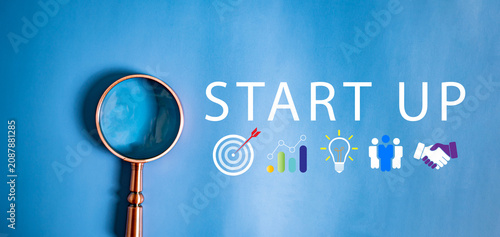Magnifying glass with Start Up text and business strategy icons on blue background