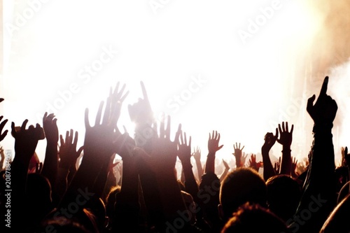 фотографія Crowd silhouettes raise hands toward bright stage lights