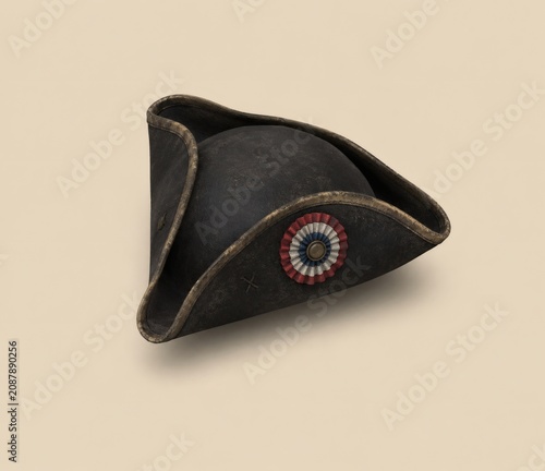 Antique black tricorn hat featuring a circular french cockade emblem isolated on a neutral beige background