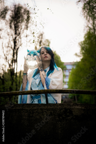 Woman in fantasy costume posing with mask among birch trees