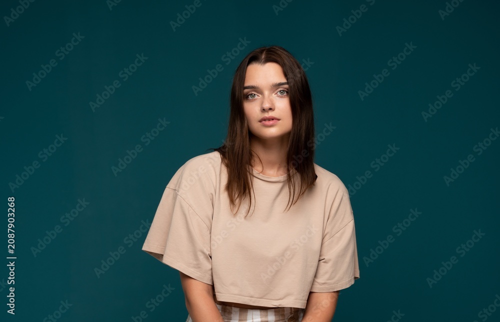Obraz premium Young brunette woman posing in studio, wearing casual attire, looking directly at camera with natural expression