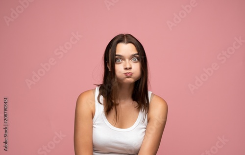 Konstfotografi Young woman making a goofy face, puffing cheeks and widening eyes