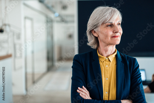 Thoughtful businesswoman with arms crossed at workplace
