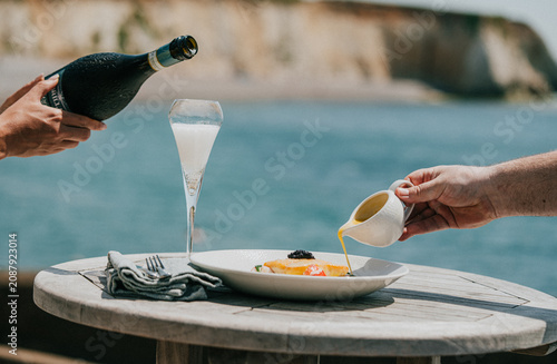 Obraz na plátně Champagne is poured over caviar and eggs on a seaside table
